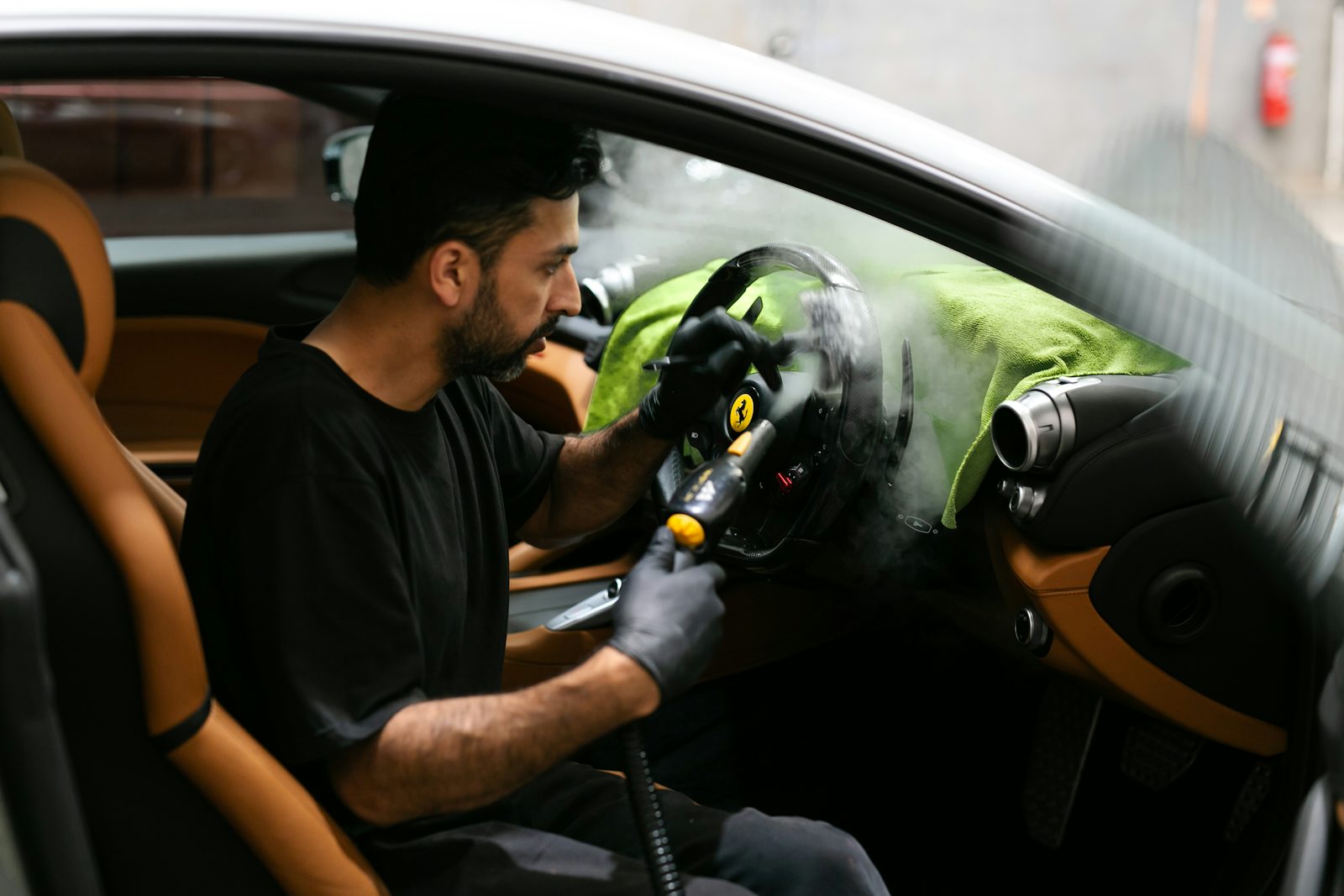Professional detailer steam cleaning a vehicle interior
